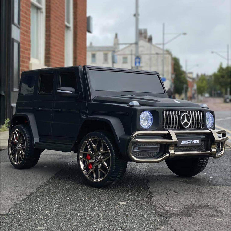 Licensed Mercedes G63 kids ride on 24V with MP4 TV in black parked on the street.