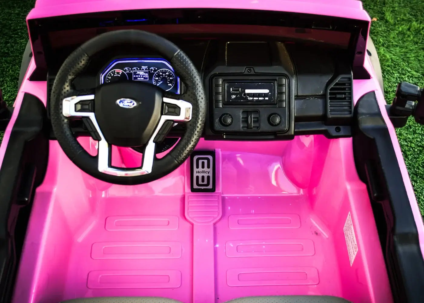 Interior view of a pink kids ride-on Ford truck featuring a steering wheel and dashboard controls.